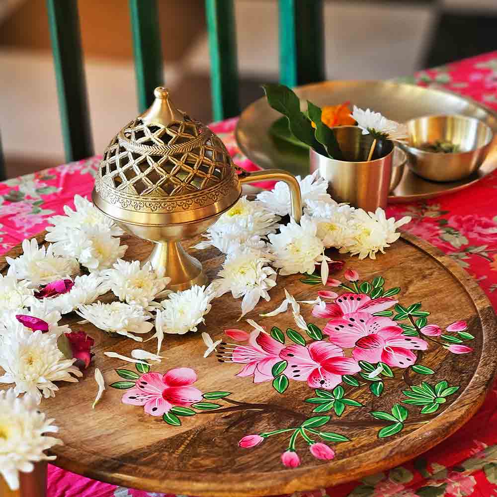 Yellow Marigold Akhand Chirag Dhuni brass lamp placed on a wooden table or altar with a diya lit — warm traditional home ambience